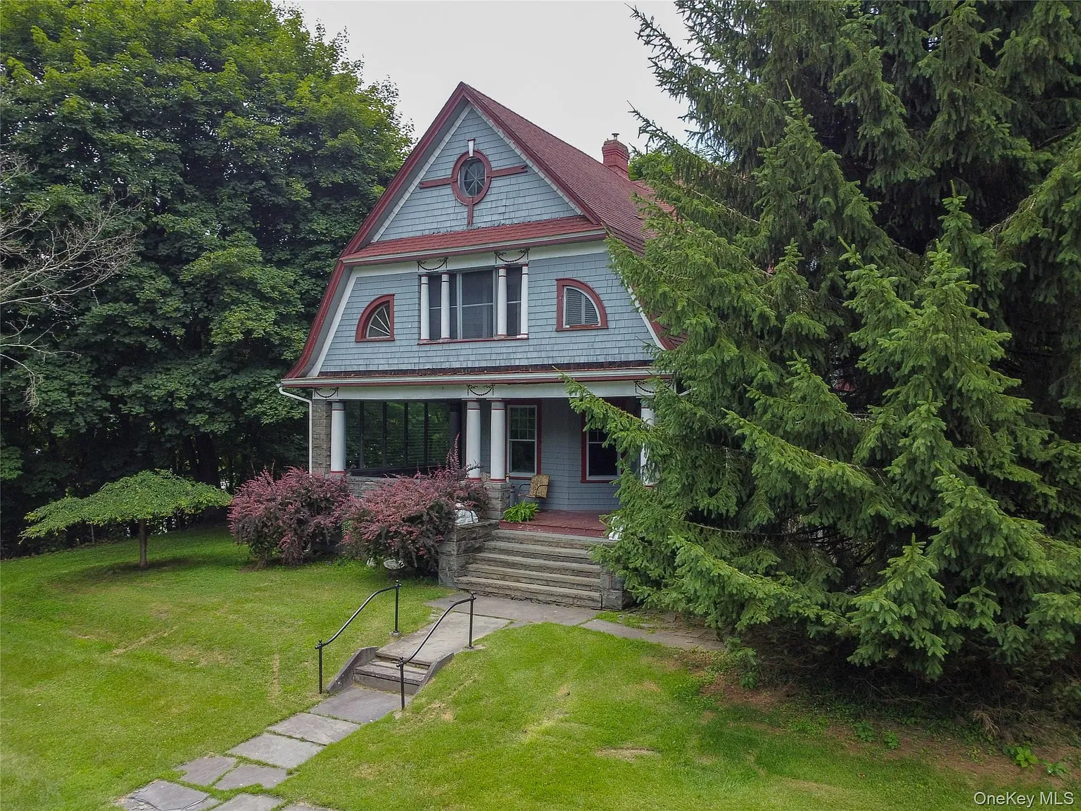 a shingle style house with blue shingles, red trim and a front porch