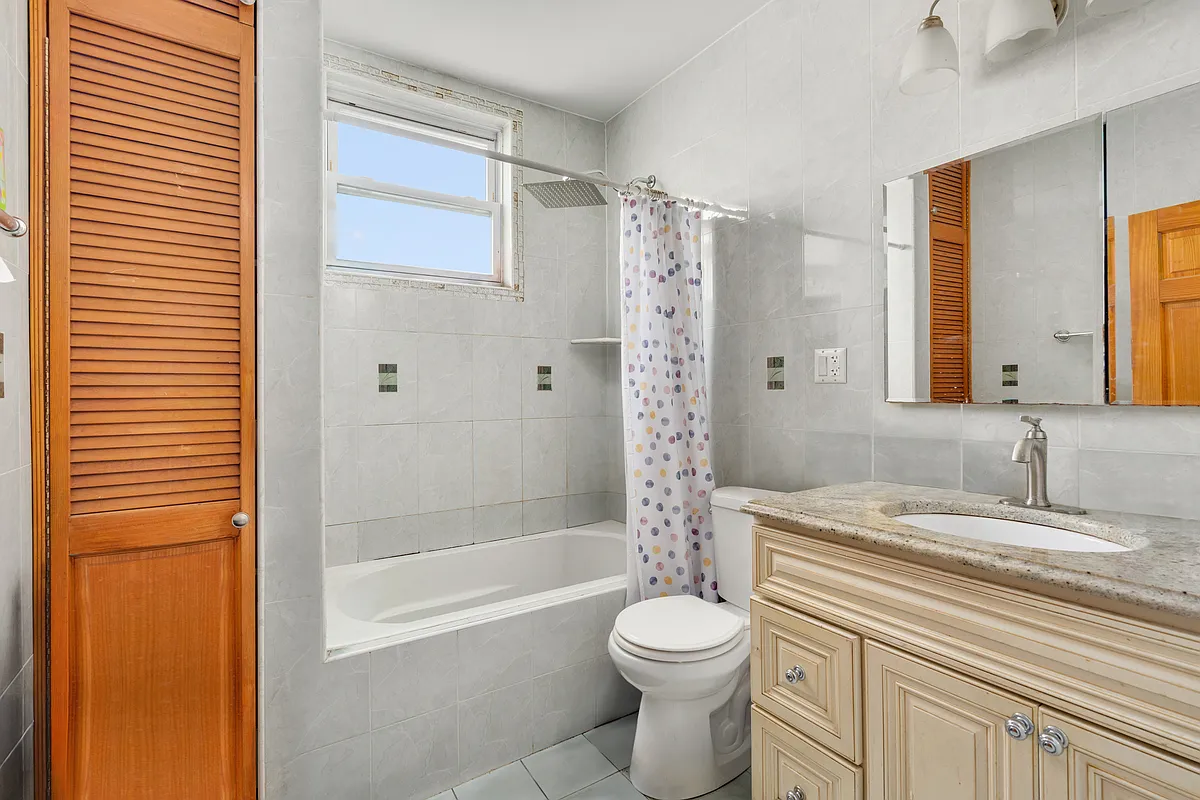 bathroom with pale wood vanity, grey tile