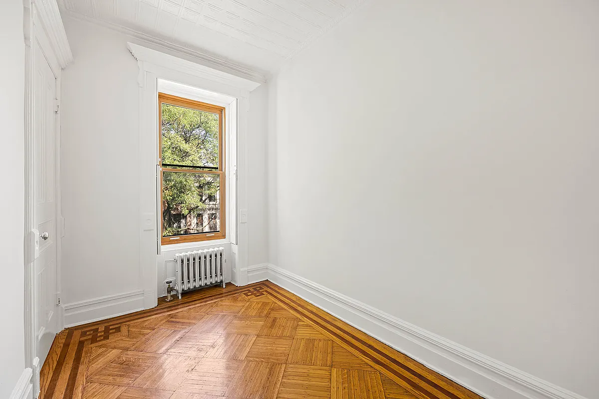 narrow bedroom with white walls wood floor