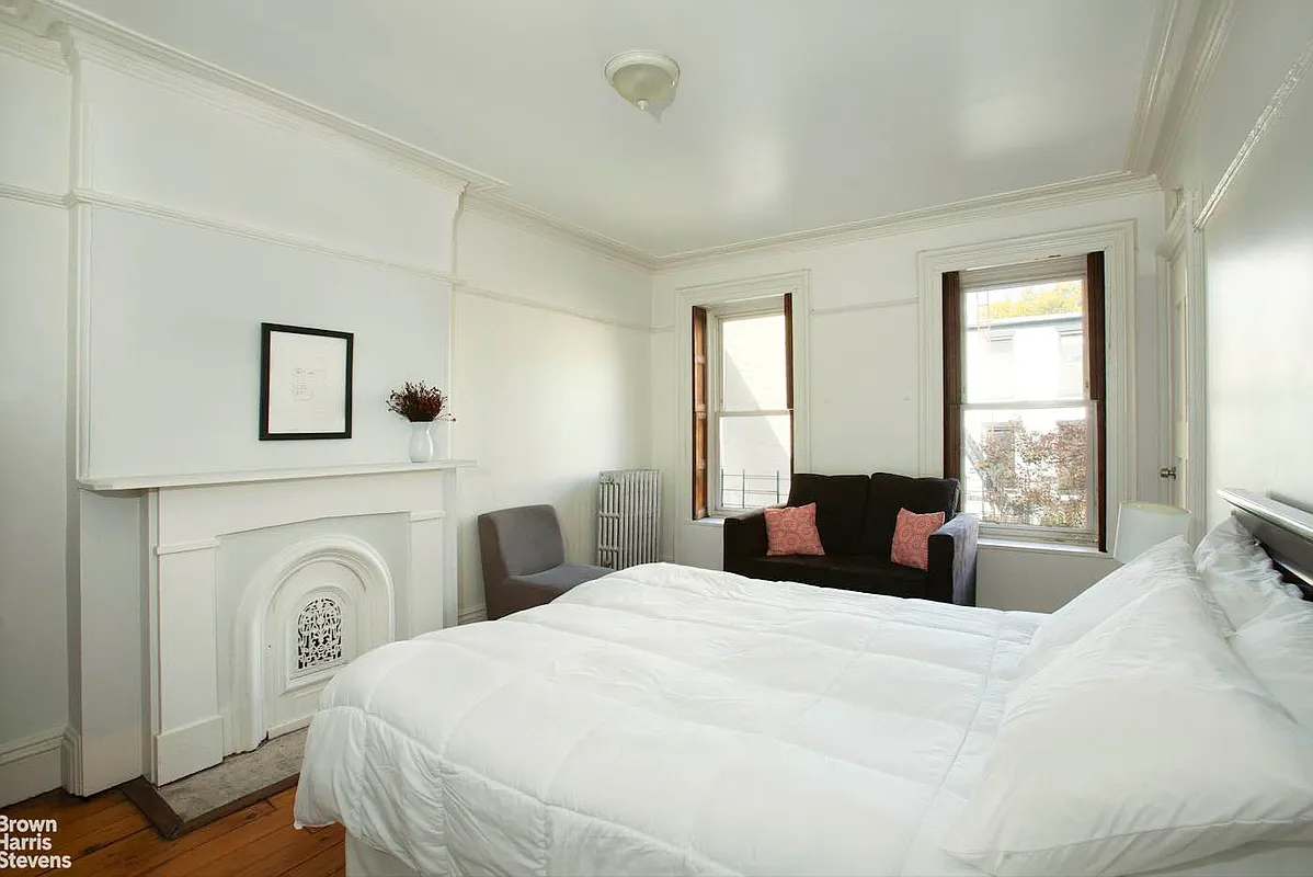 bedroom with white mantel, picture rails, wood floor