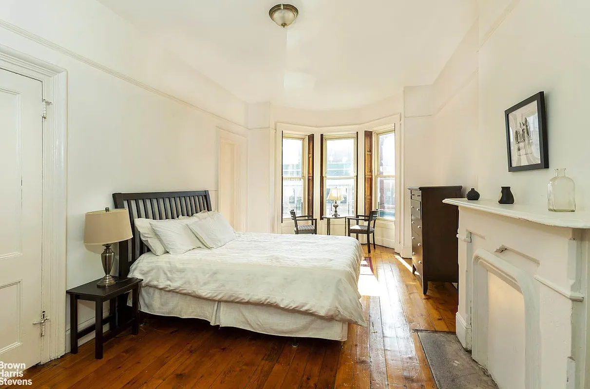 bedroom with white painted mantel, wood floor