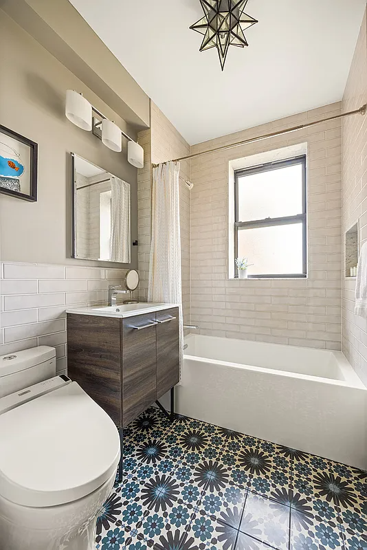 bathroom with graphic blue and black floor tile, wood vanity, white fixtures