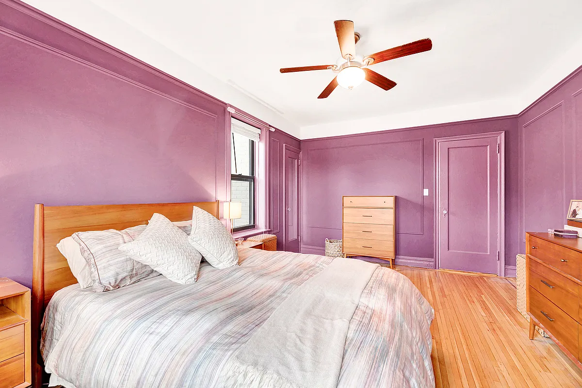 bedroom with two exposures, wall moldings, purple paint, wood floor
