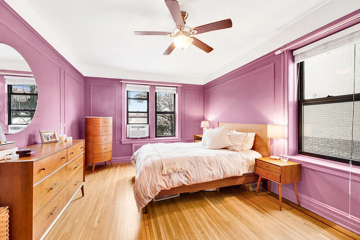 bedroom with two exposures, wall moldings, purple paint, wood floor