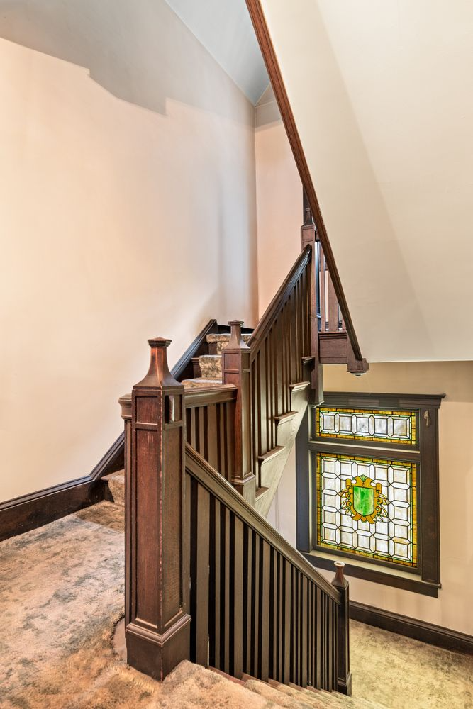 carpeted steps with a stained glass window at the staircase landing