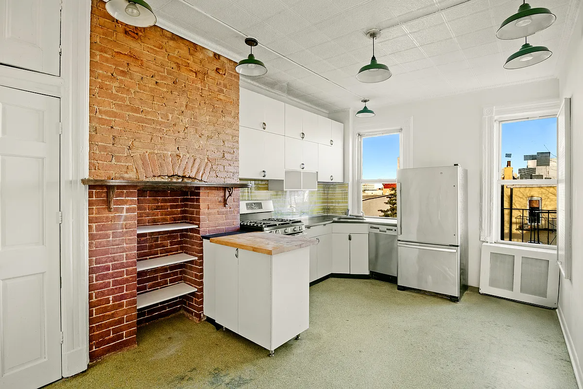 kitchen with brick fireplace, white cabinets, tin ceiling
