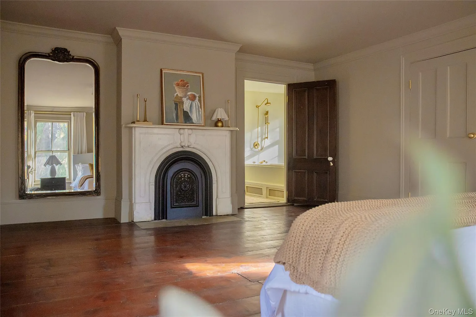 bedroom with marble fireplace and view into a bath