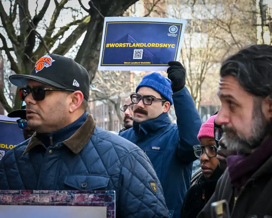 person in blue hat holds a sign