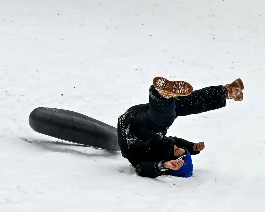 A sledder tumbles while going down the hill.