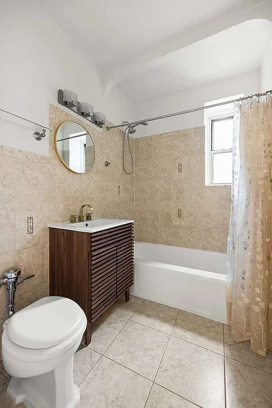 bathroom with beige floor and wall tile, wood vanity