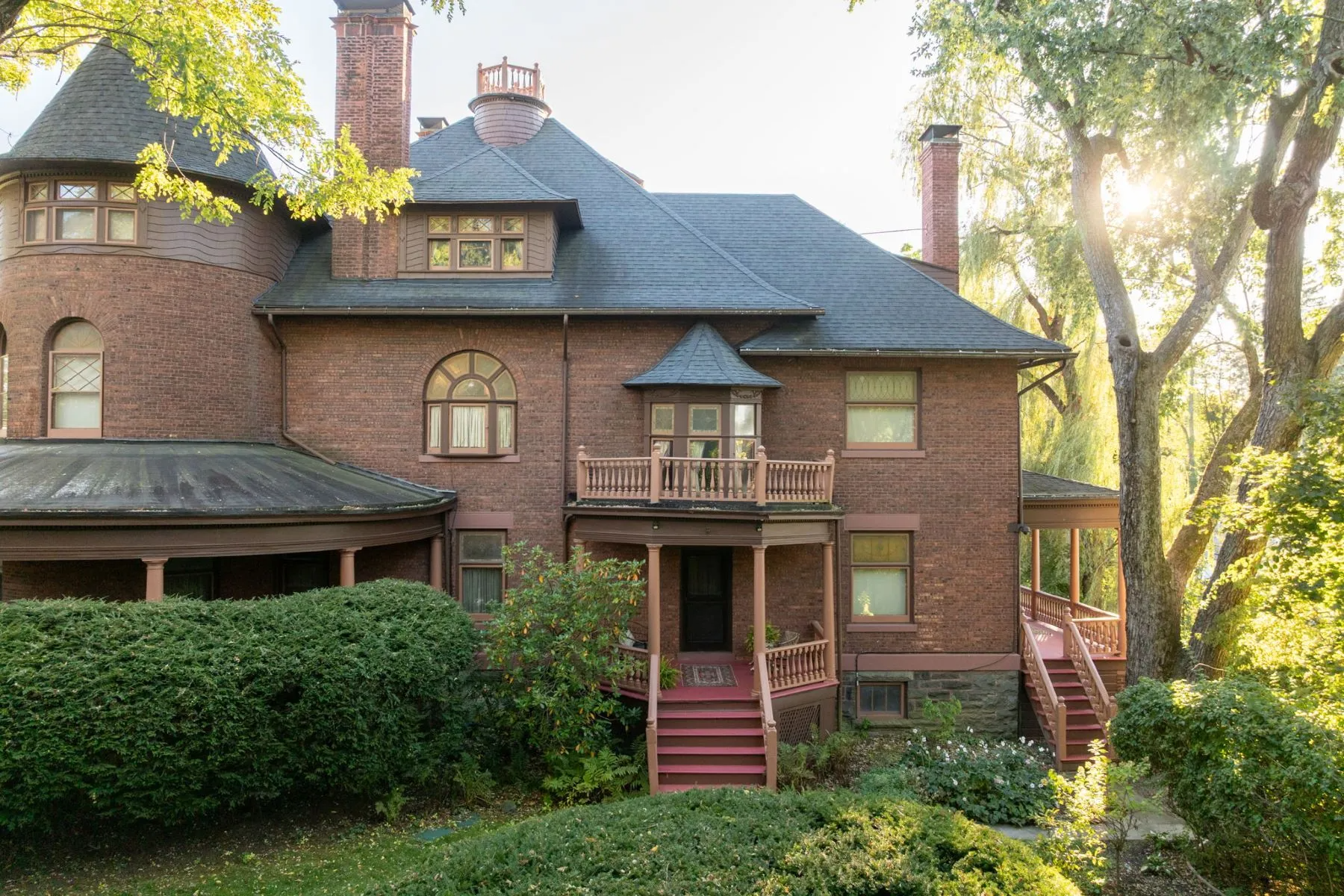 exterior of brick house with porches, rounded bay, chimneys