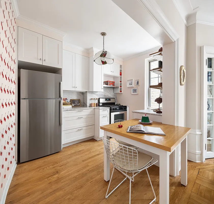 kitchen with white cabinets, cherry wallpaper on one wall