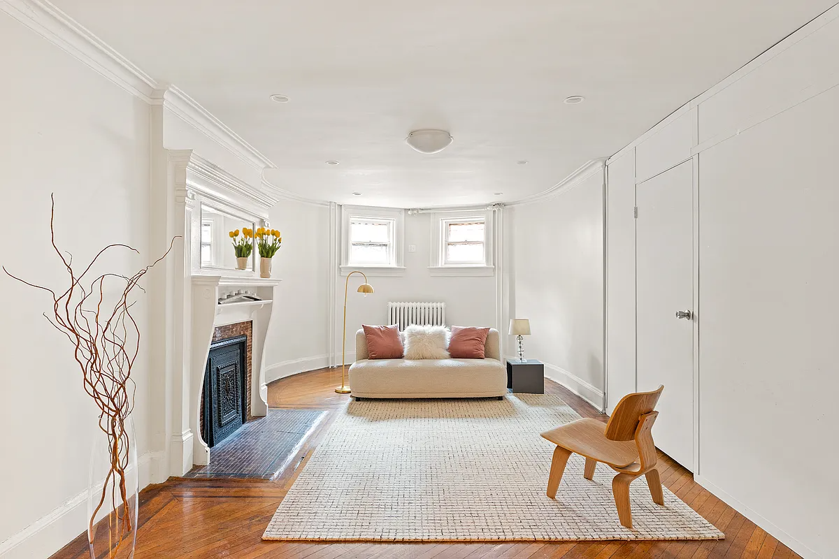 garden level apartment living room with a white painted mantel and a wood floor
