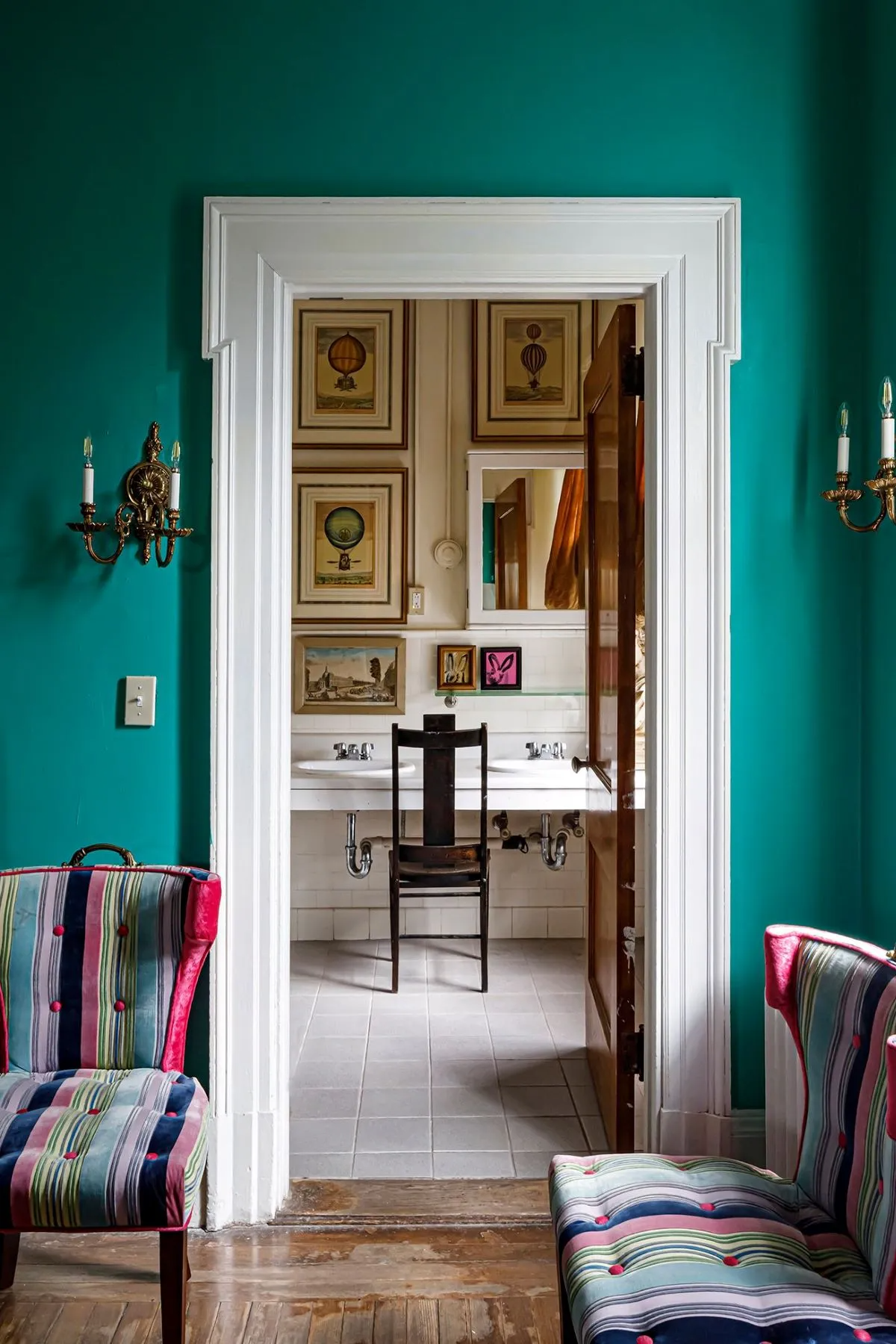 bedroom with green walls and a view into a bathroom with twin vanity