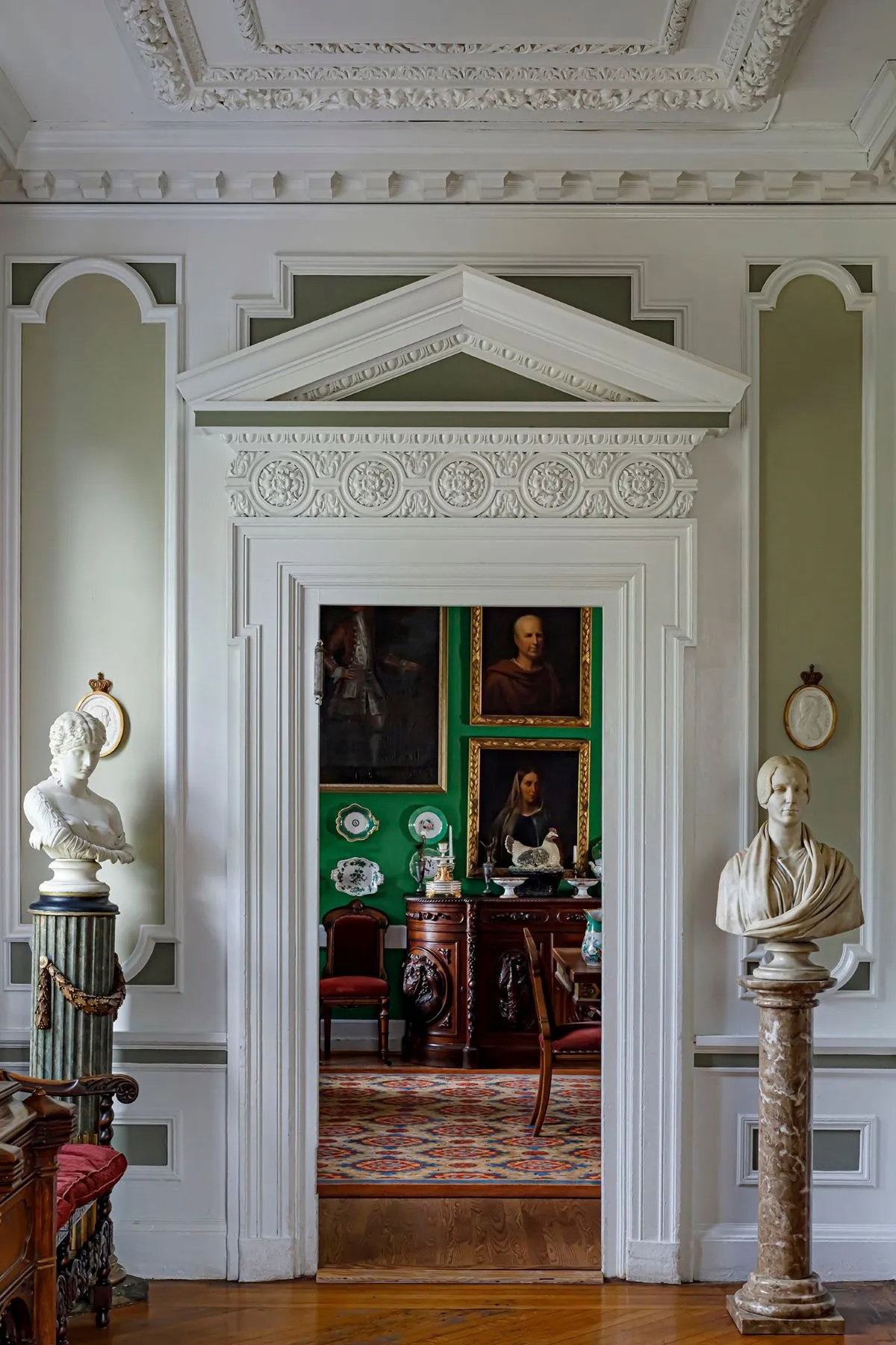 elaborate door surround with view into bright green dining room
