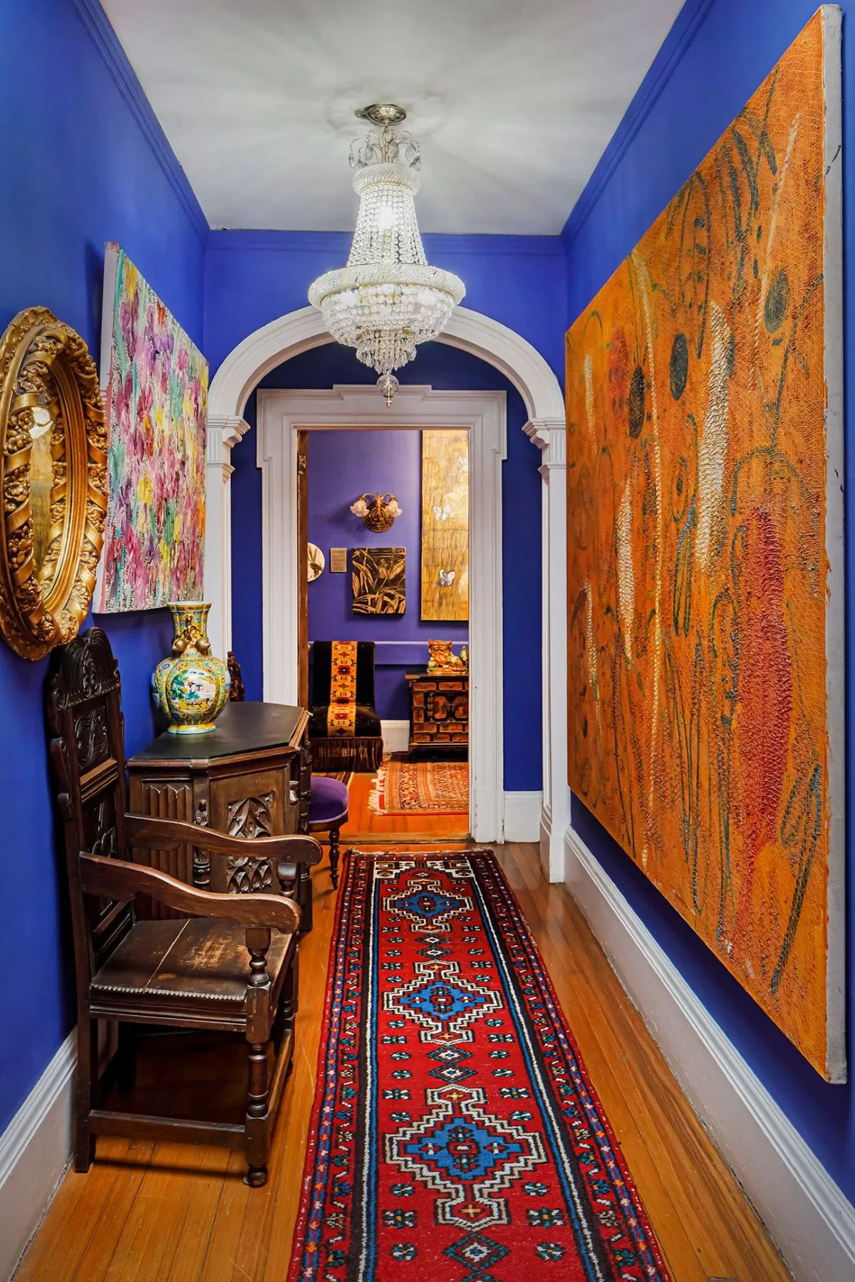 hallway with bright blue walls, doorways with arched molding and greek ear molding