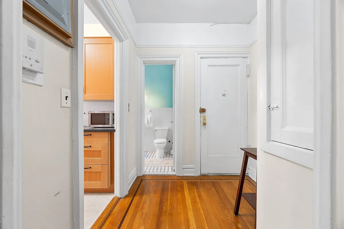 foyer with wood floor and view into the kitchen and bathroom