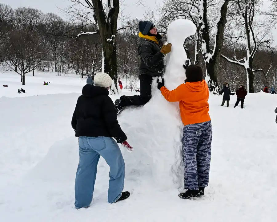 group of friends building a snow creature