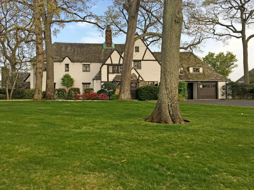 warmer weather view of the house with a lawn and a driveway