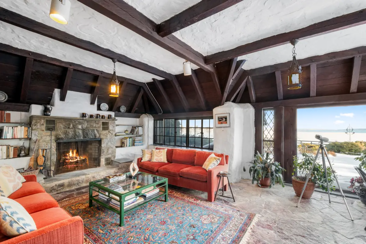 family room or den with large stone fireplace, beamed ceiling, stone floor