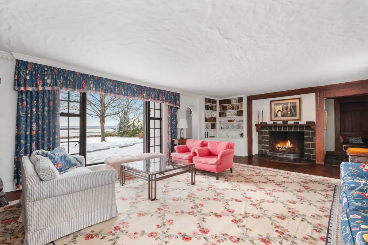 living room with built-in bookcases, stone fireplace, large windows