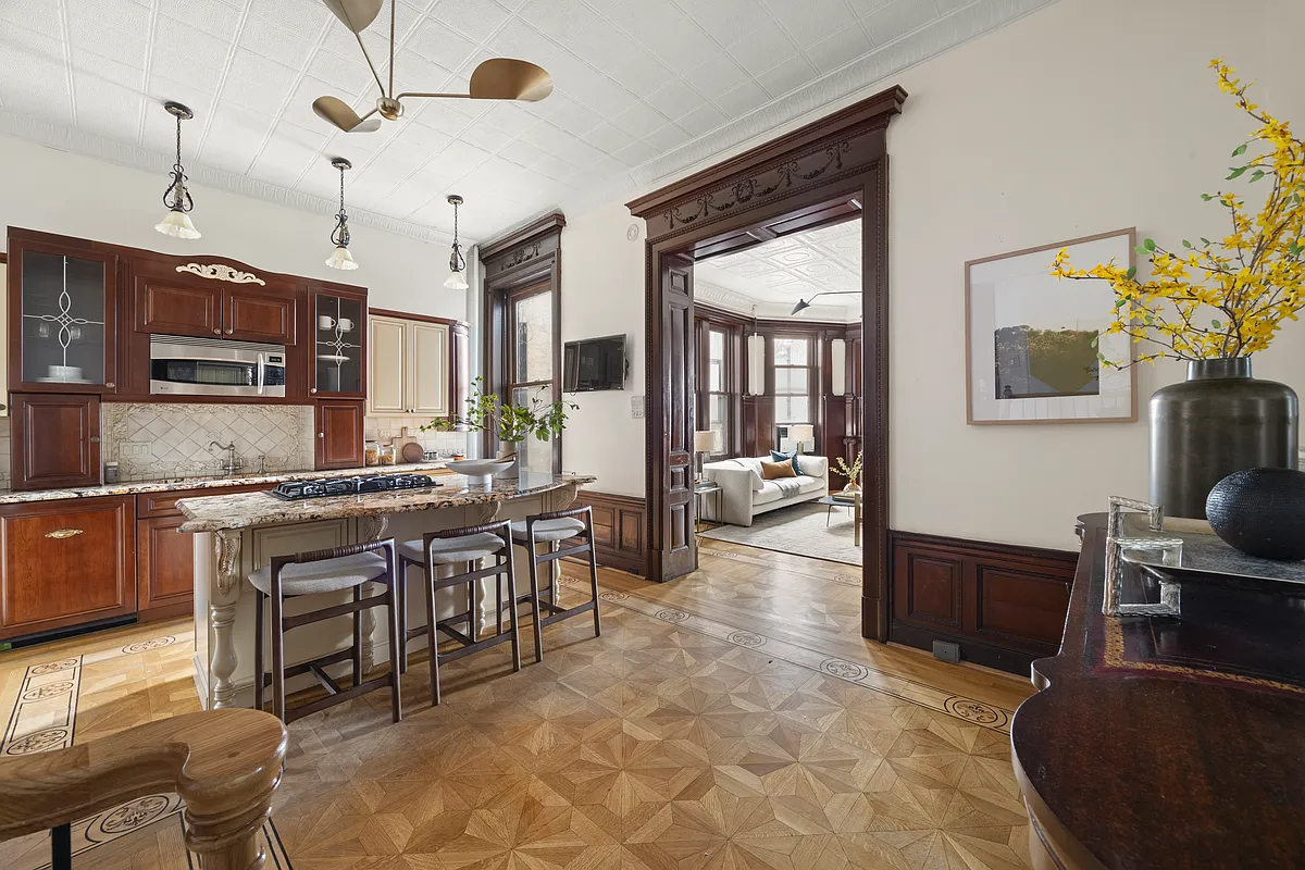 eat-in kitchen with wood cabinets, a large island, original moldings and a tin ceiling