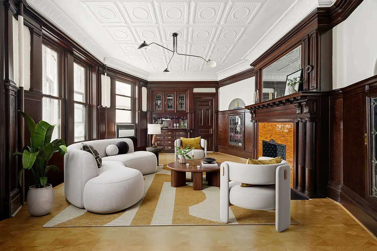 virtually staged living room with white, curved furniture in a room with original built-ins, a mantel, and a tin ceiling