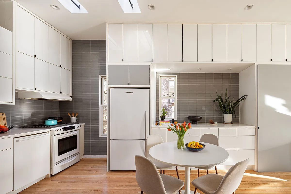 kitchen with slab front white cabinets - gray backsplash