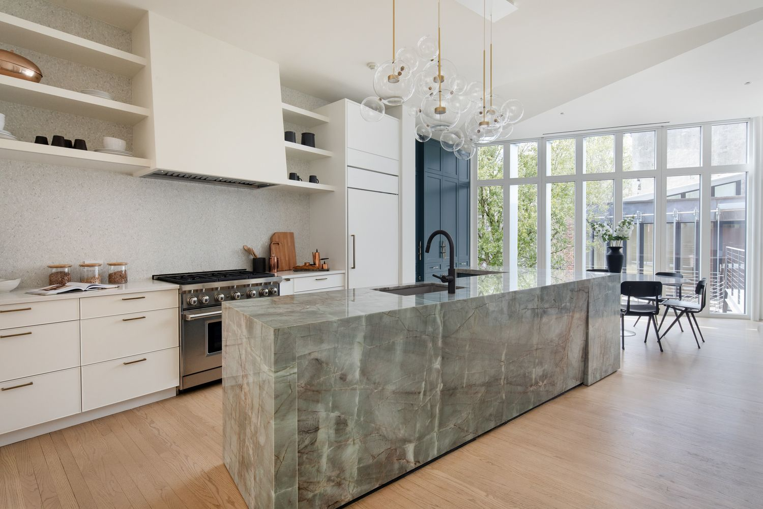kitchen with massive marble island, white cabinetry and a wall of glass