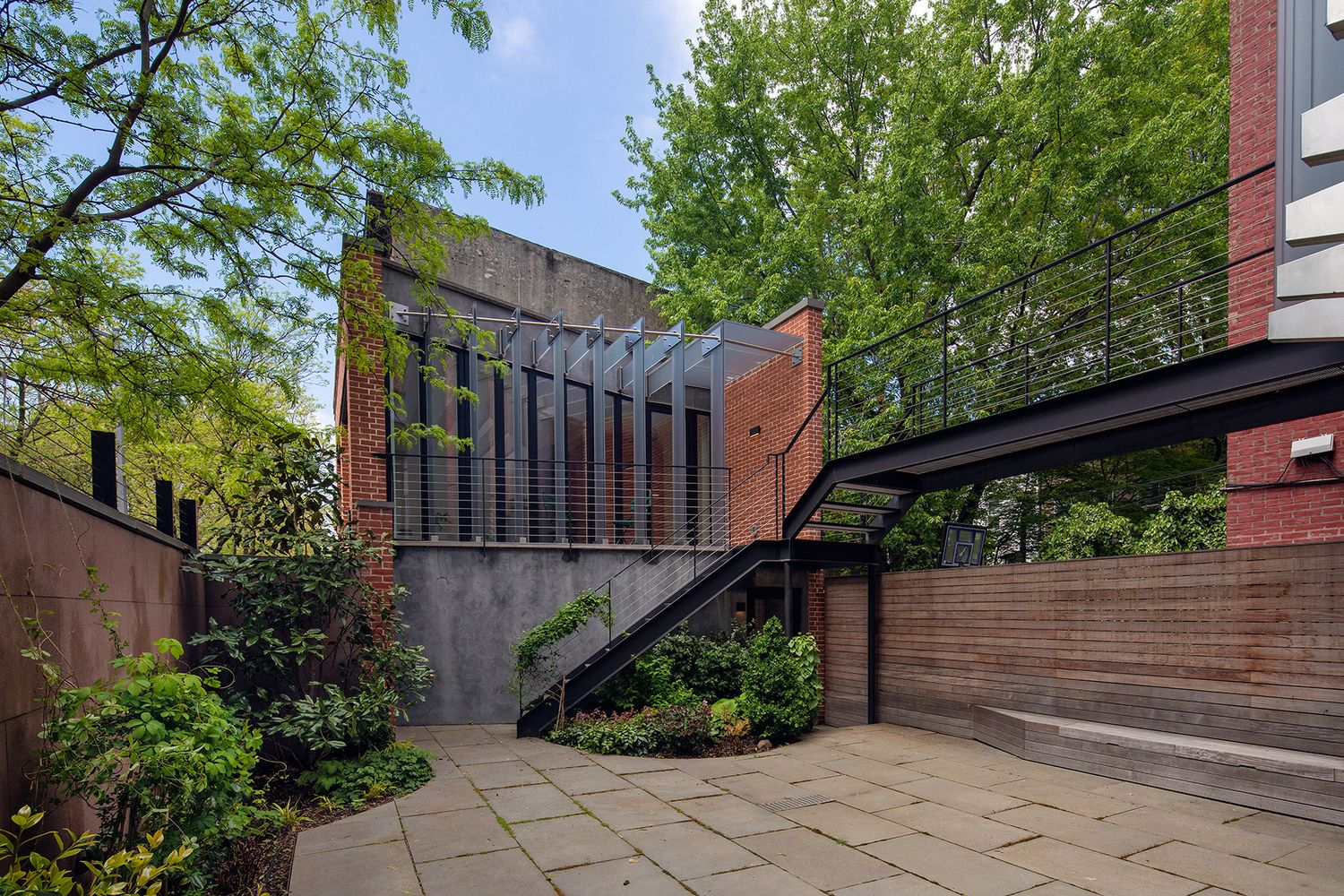 paved rear yard with view of iron catwalk to office space above garage