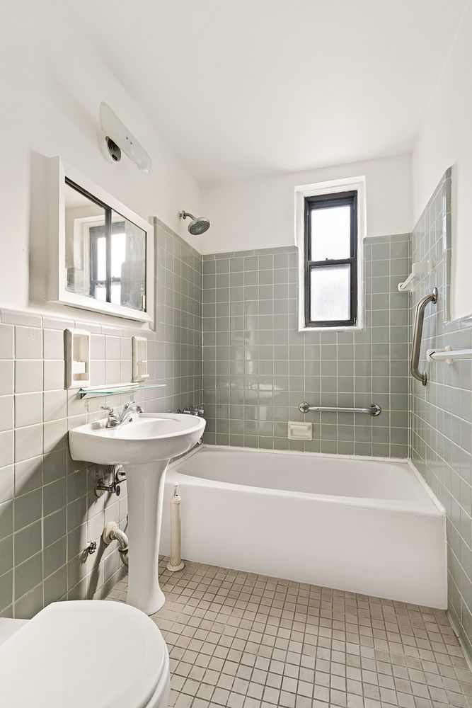 bathroom with gray wall tiles, white fixtures