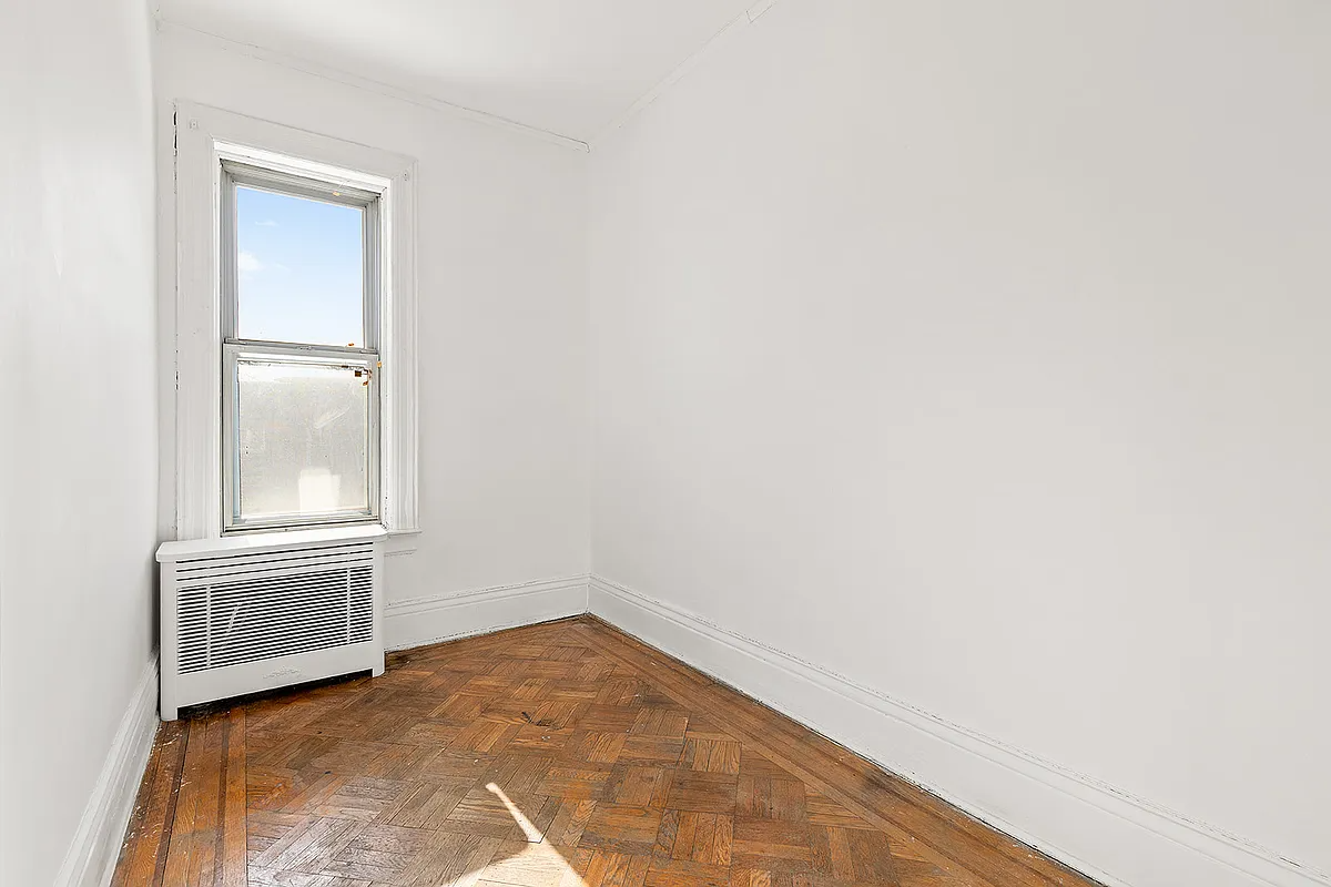 narrow bedroom with wood floor, one window