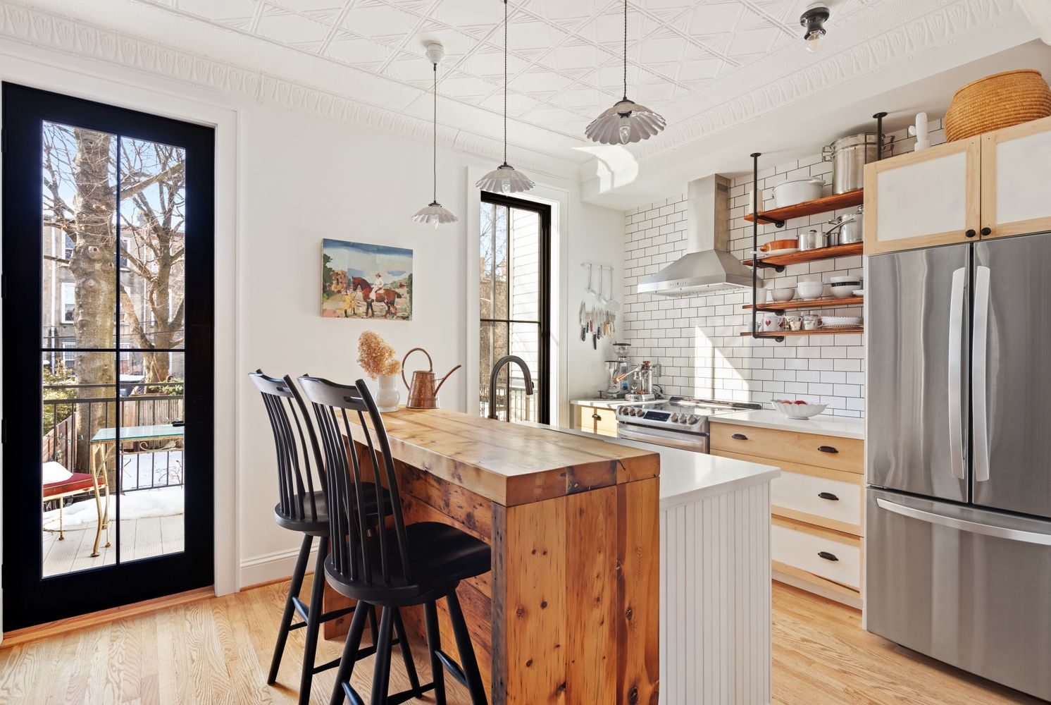 kitchen with island with room for seating, white subway tiles, doors to deck