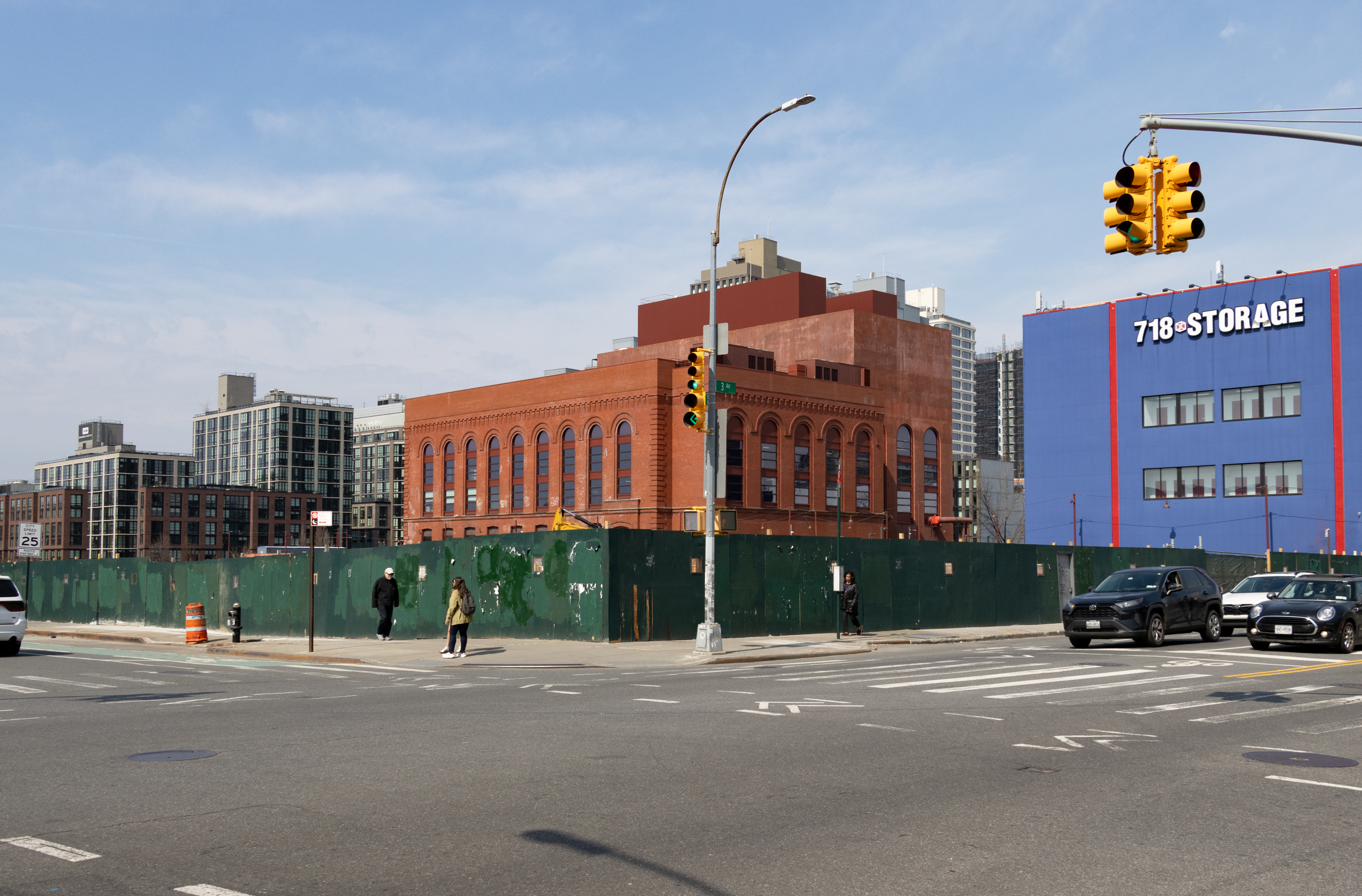 green construction fence around an empty lot with old and new buildings in the background