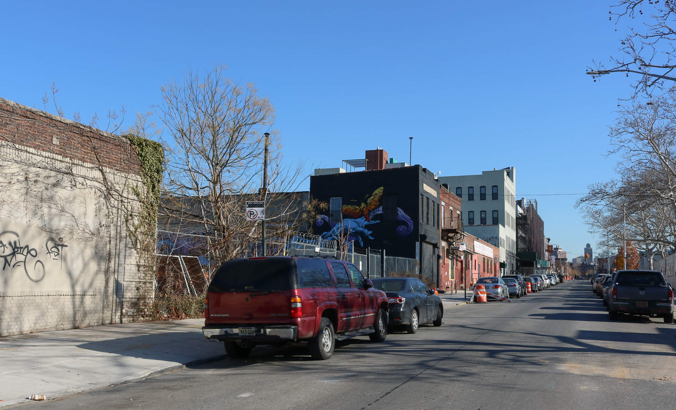 block showing a lot behind a chain link fence and some low scale industrial buildings