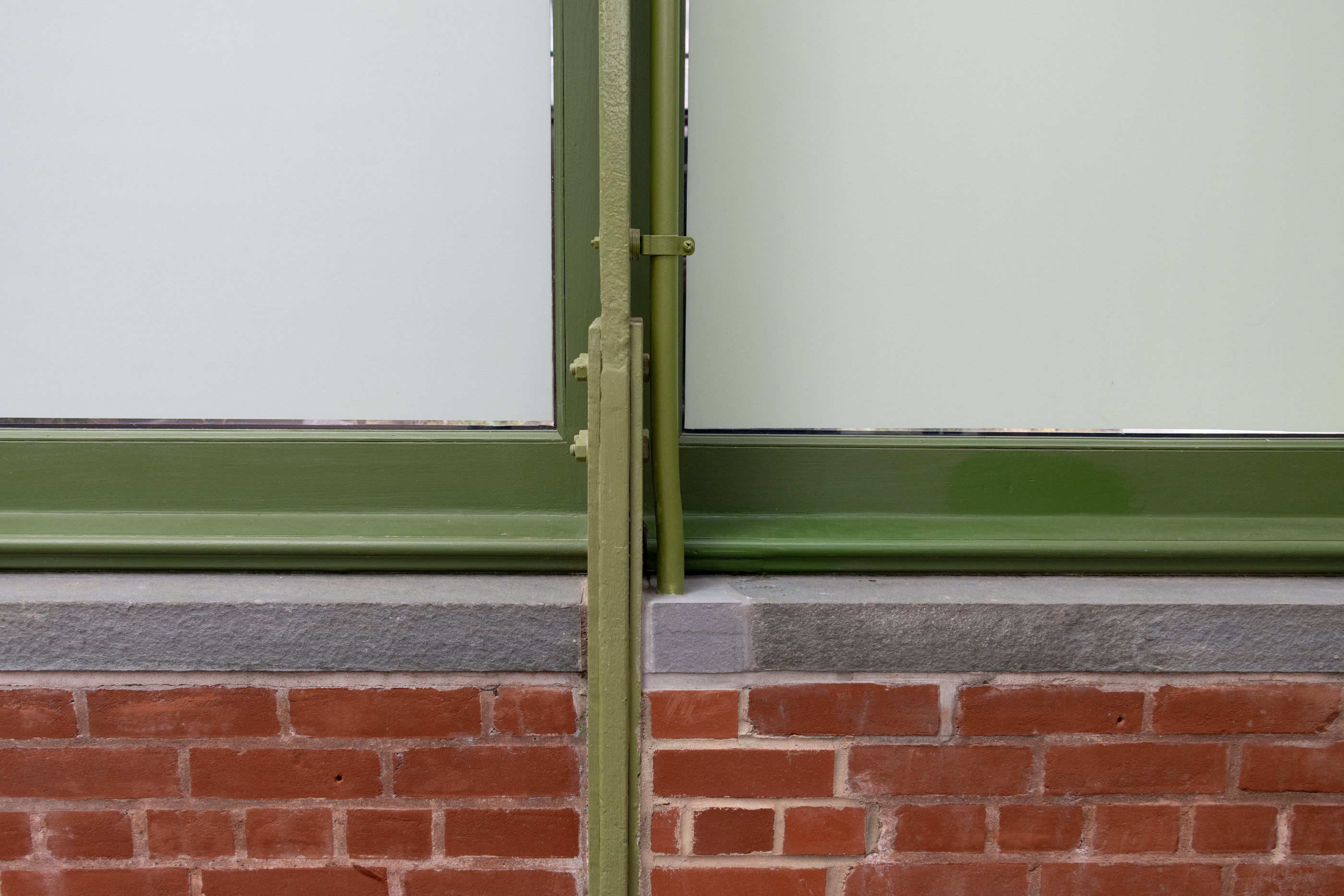 brick wall and green ribbing of the interior of the greenhouse