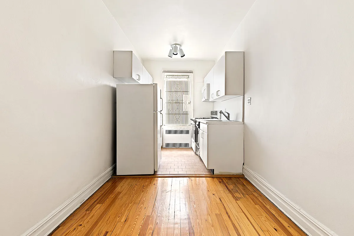 kitchen with white cabinets, terra cotta tile floor and a dining nook with a wood floor