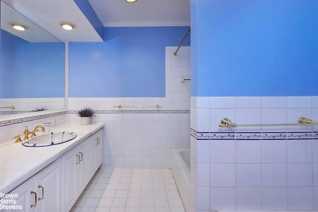 bathroom with white cabinets, tile, blue walls