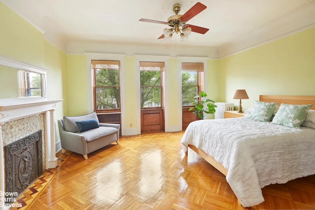 bedroom with white mantel, picture rail, ceiling fan