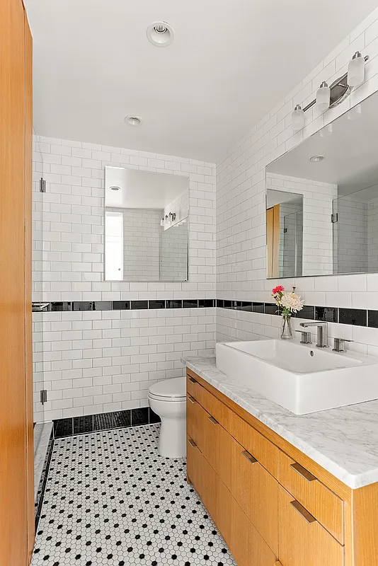 bathroom with wood vanity, shower, black and white floor tile