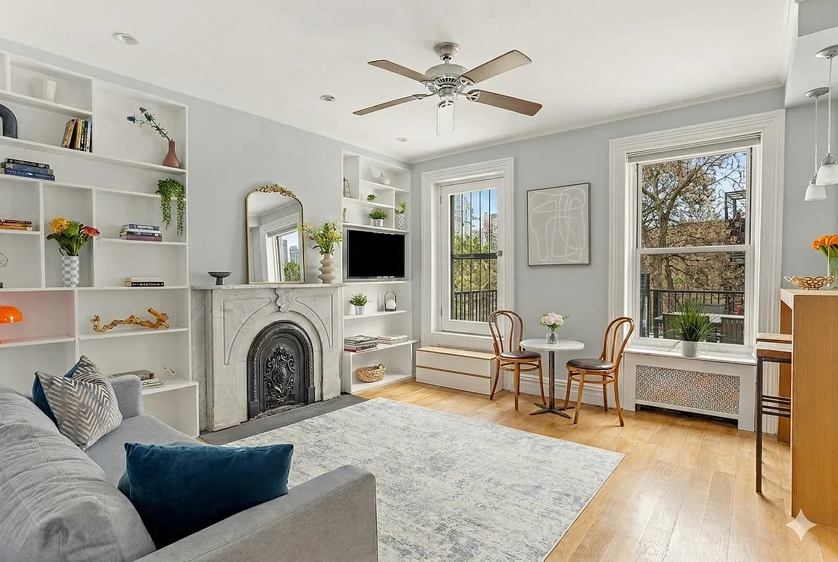 living room with built-ins on either side of a marble mantel, steps up to a door to terrace