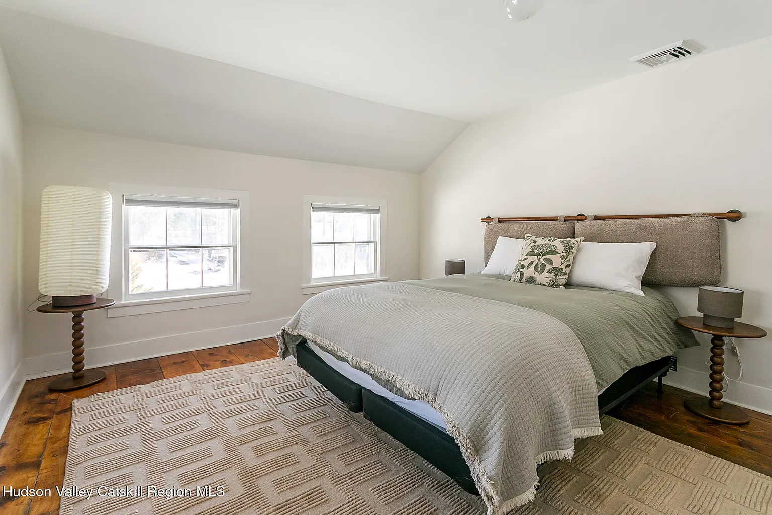upstairs bedroom with angled ceiling, wood floor