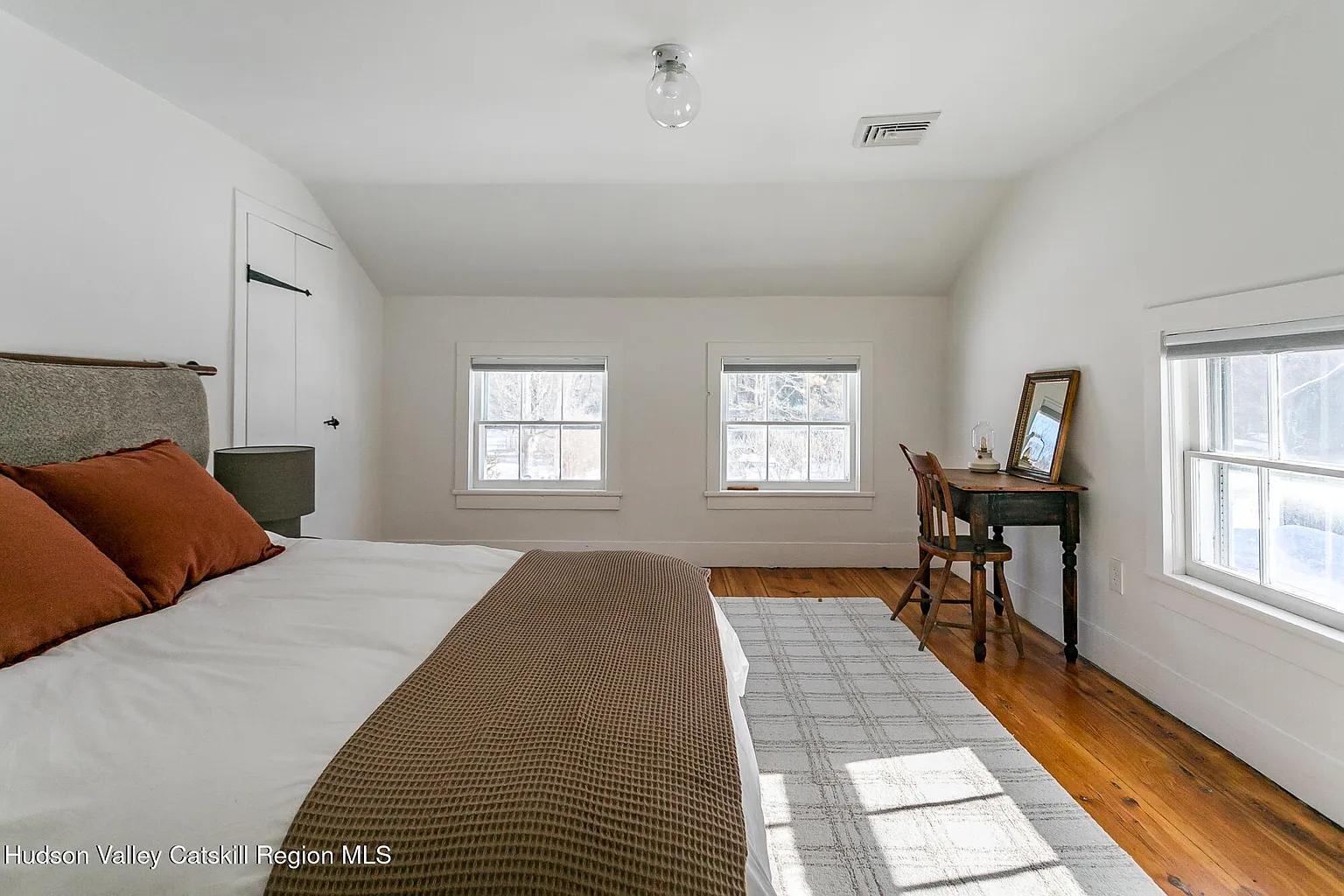 upstairs bedroom with angled ceiling, wood floor