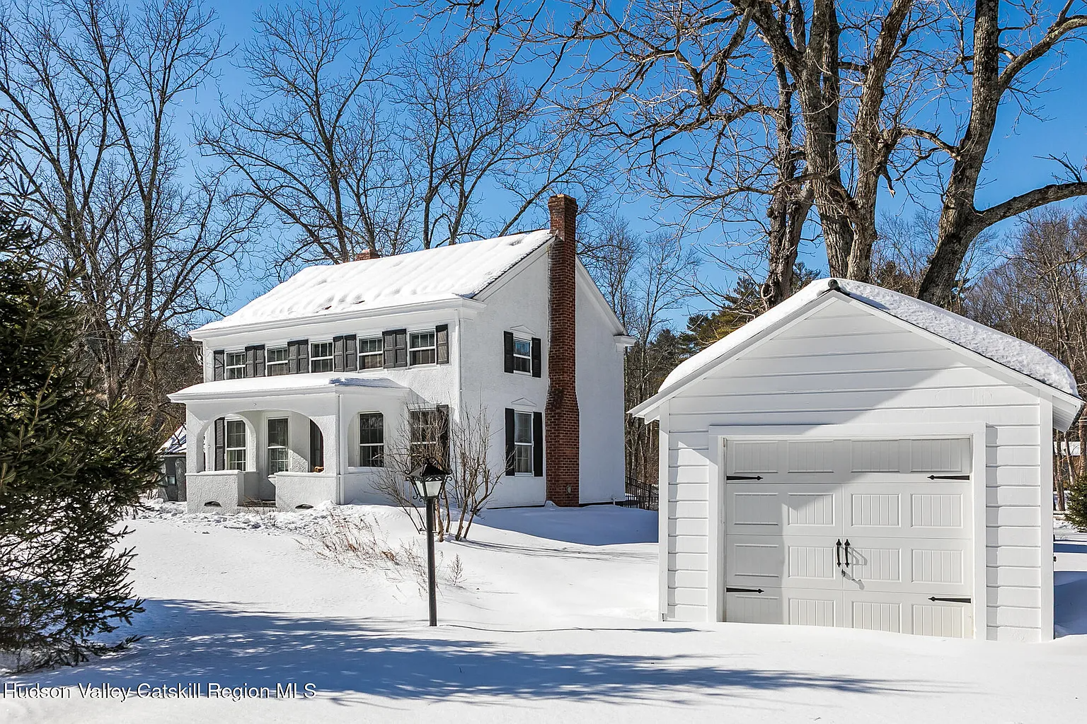 white stucco covered farmhouse with a separate garage