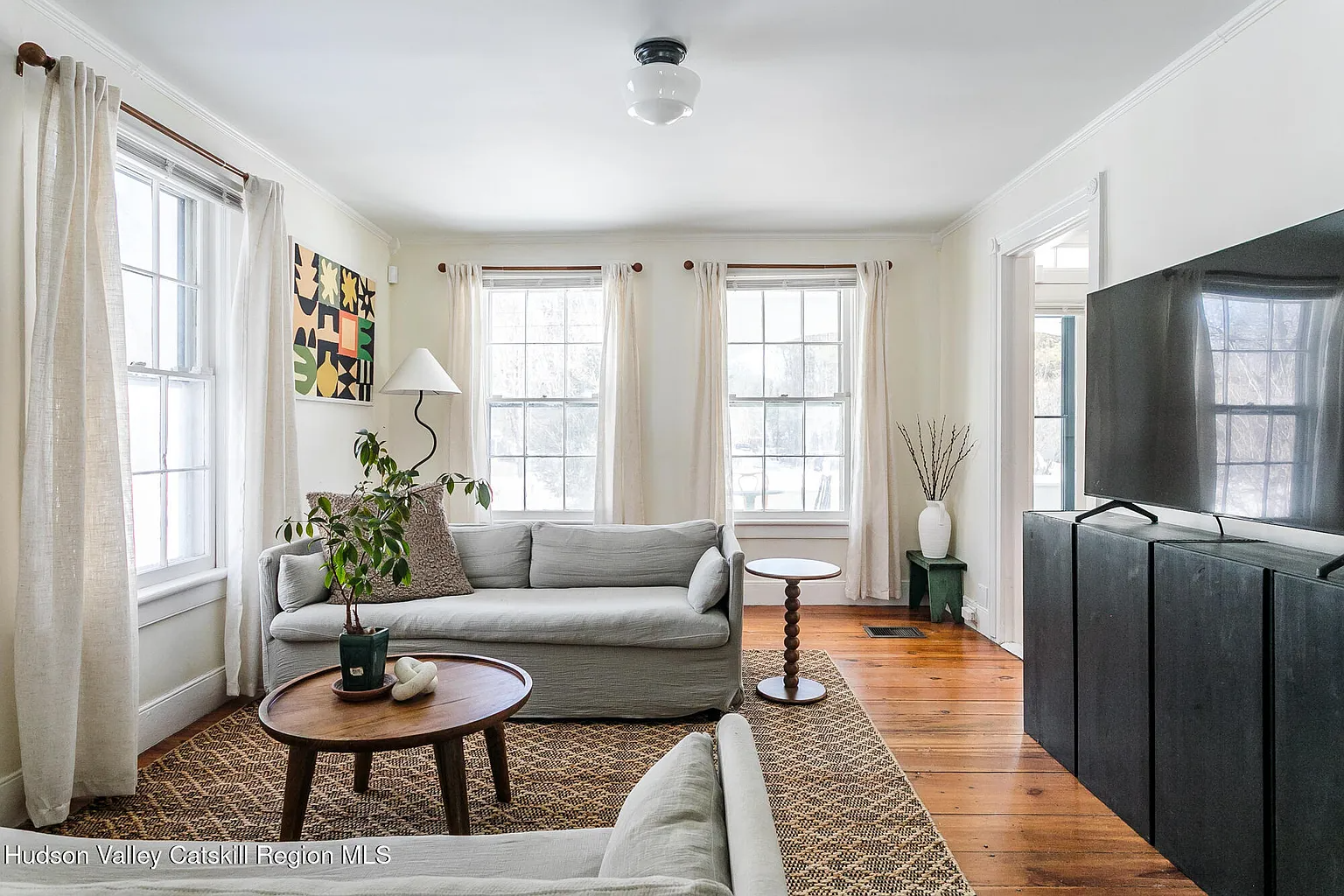a living room with white walls, wide planked floorboards
