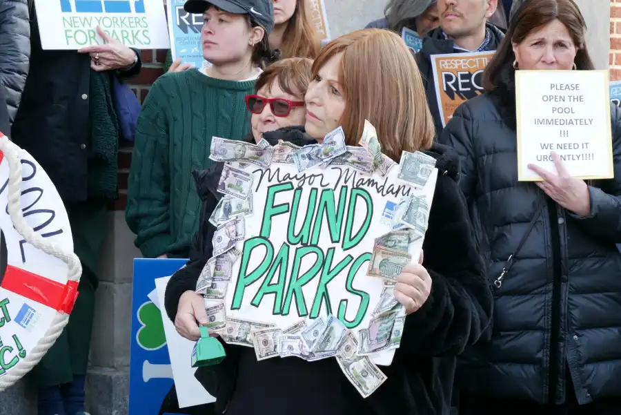 person holding a sign saying "fund parks"