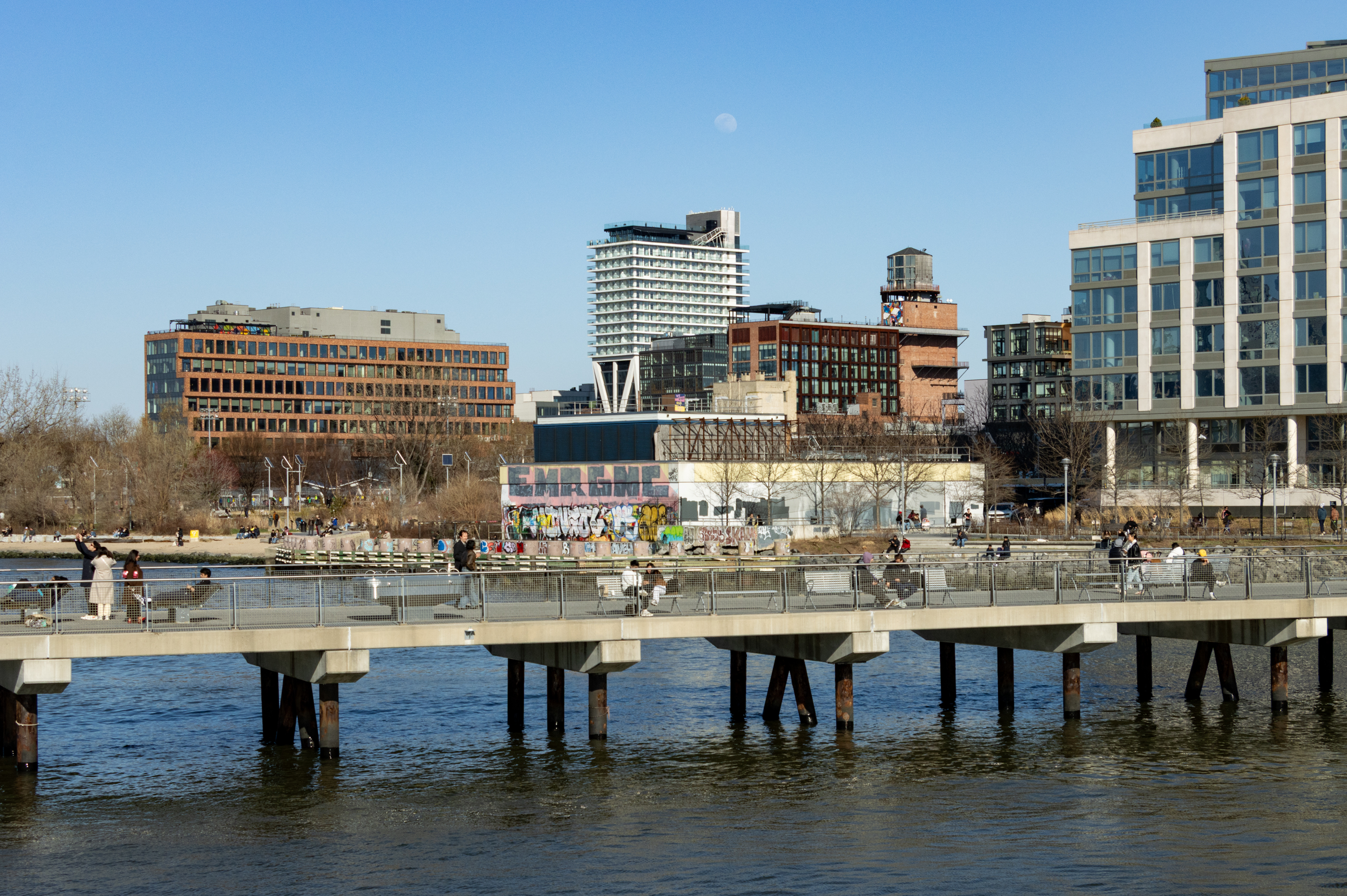 waterfront with people sitting on a pier and buildings visible behind
