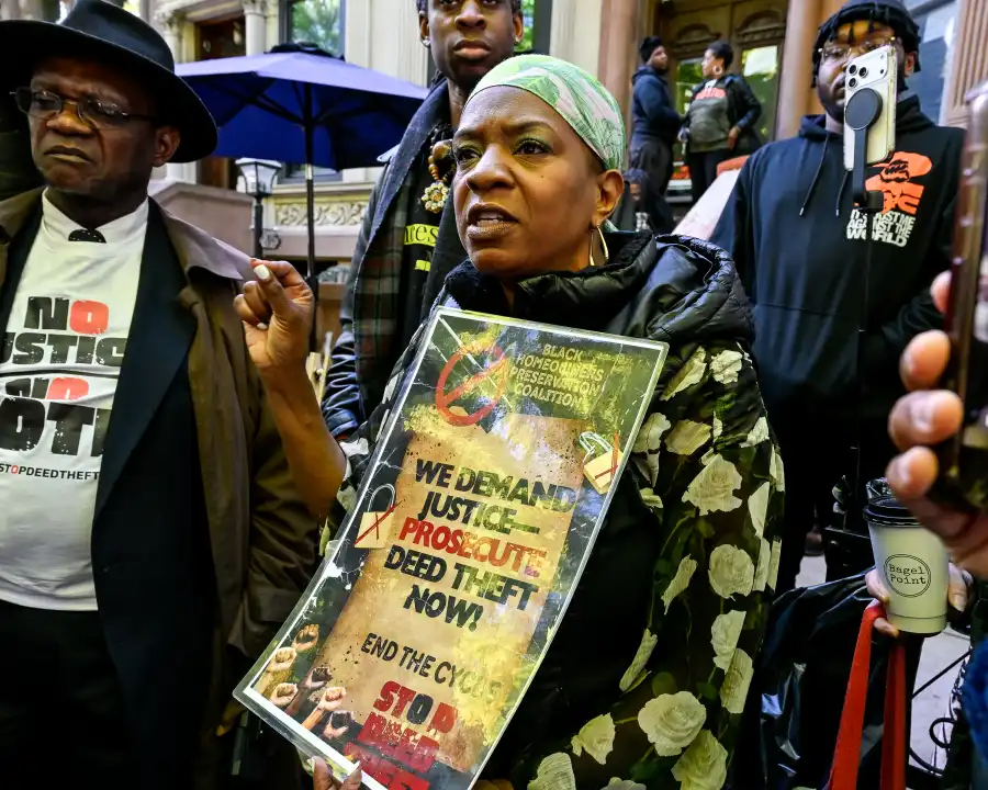person holding sign against deed theft