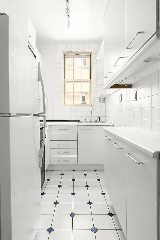 kitchen with white cabinets, backsplash and fridge