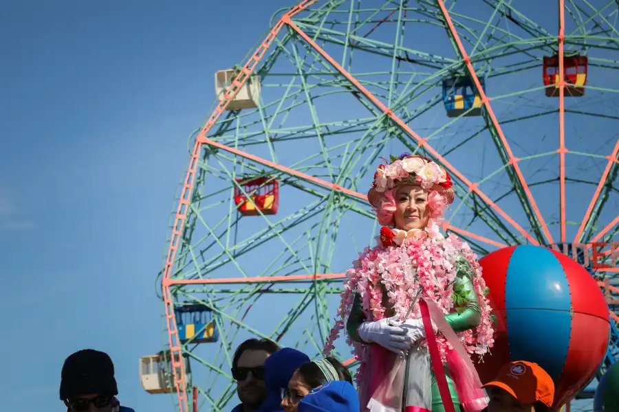 a performer in costume poses near the wonder wheel